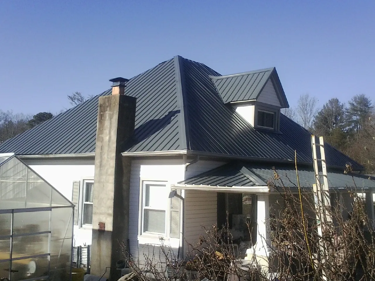 Dark blue standing seam metal roof on a white farmhouse with dormer — Slate & Tile Roof Repair by Roofing Brothers in Powells Point