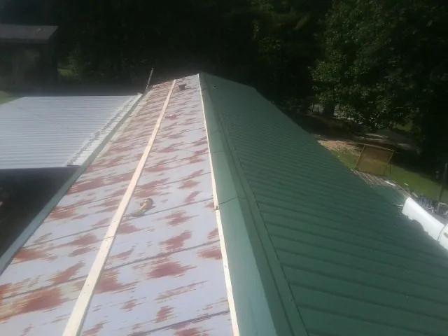 Old rusted panels beside newly installed green metal roofing — Wind Damage Roof Repair by Roofing Brothers in Powells Point