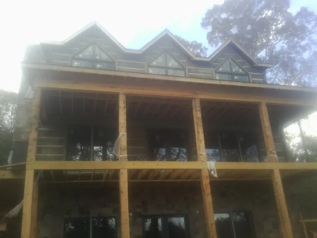 Dormers and porch framing on a large log home under construction — Roof Coating work by our crew in Powells Point