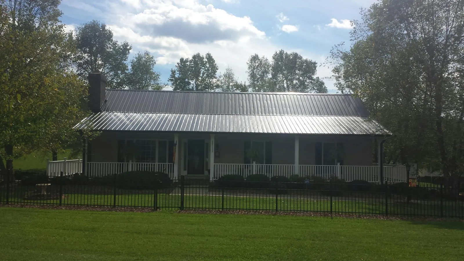 Gray metal roof on a brick ranch with a full width front porch — Gutter Guard Installation work by our crew in Powells Point