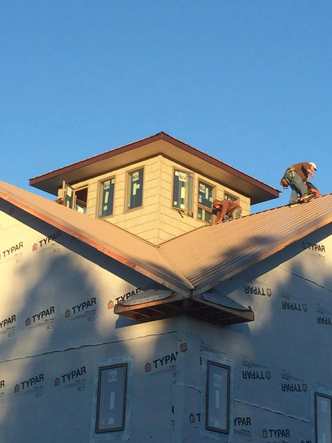 Roofers working around a rooftop cupola on a new metal roof at sunset — Roof Waterproofing in Powells Point by Roofing Brothers